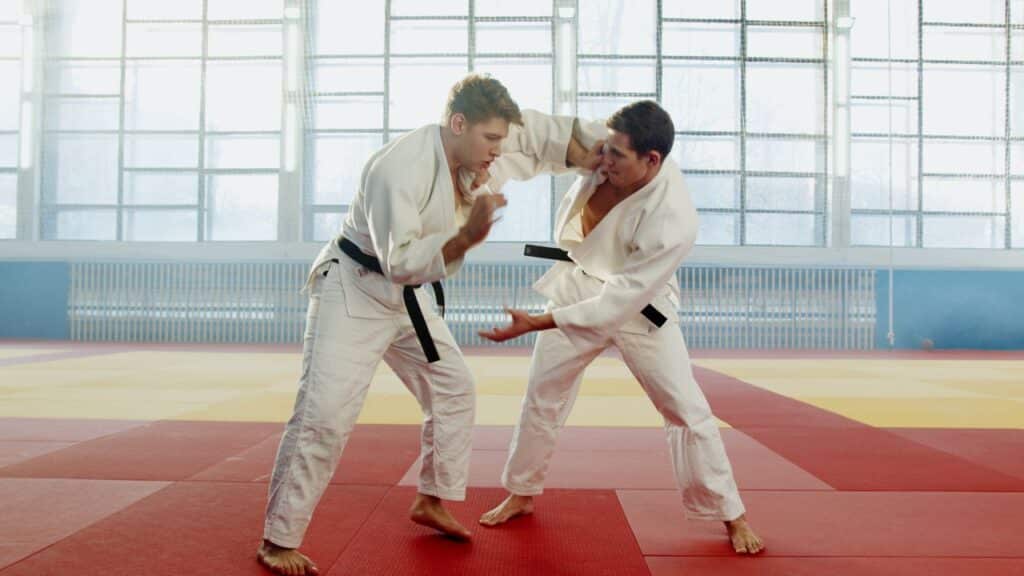 Deux judokas s’entraînent ensemble sur un tatami dans un dojo.